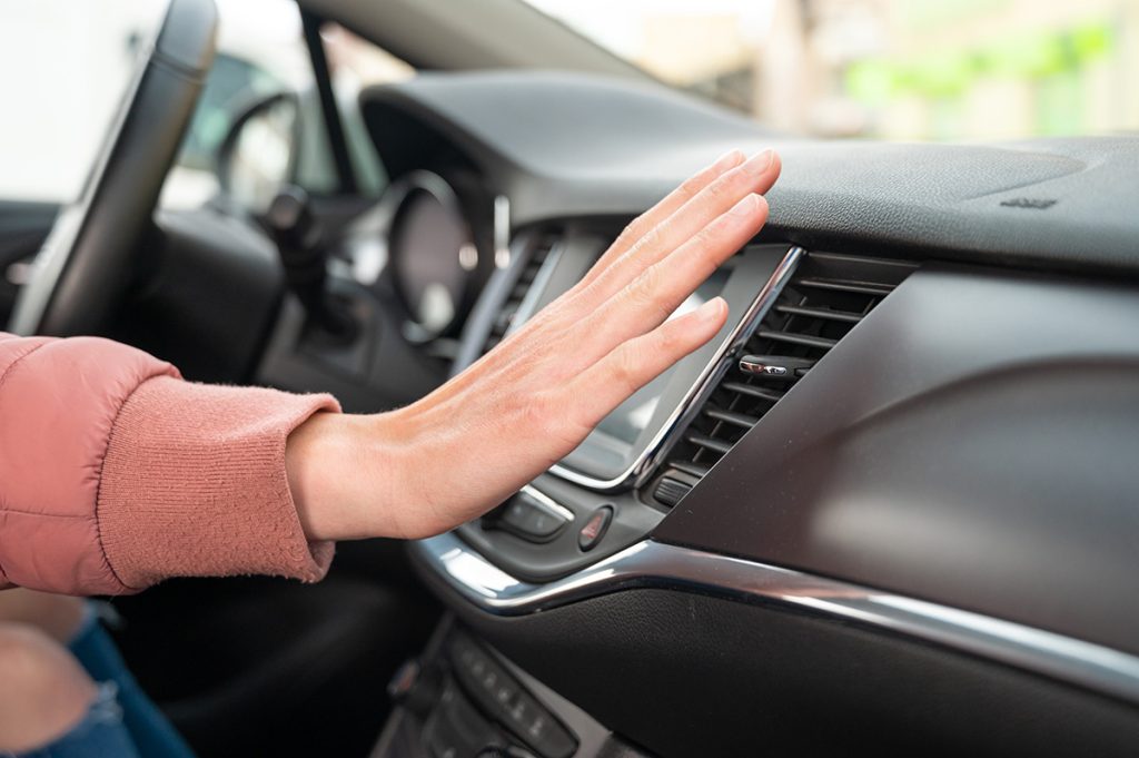 A hand hovering over the air conditioning vent - Summer Car Service Tips for Brooklyn, CT Drivers