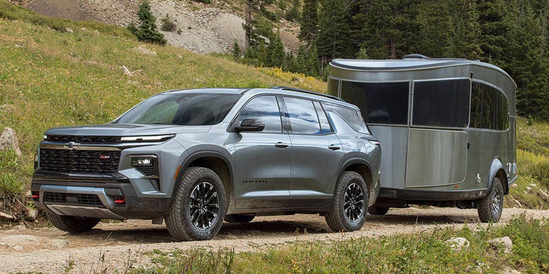 Chevrolet Traverse SUV towing a travel trailer through a scenic mountain landscape